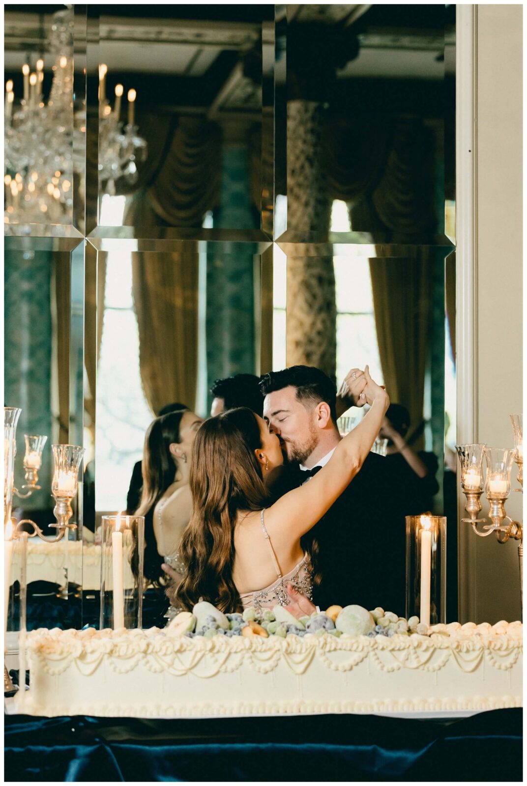 Newlyweds kiss next to custom wedding cake at The Drake Hotel