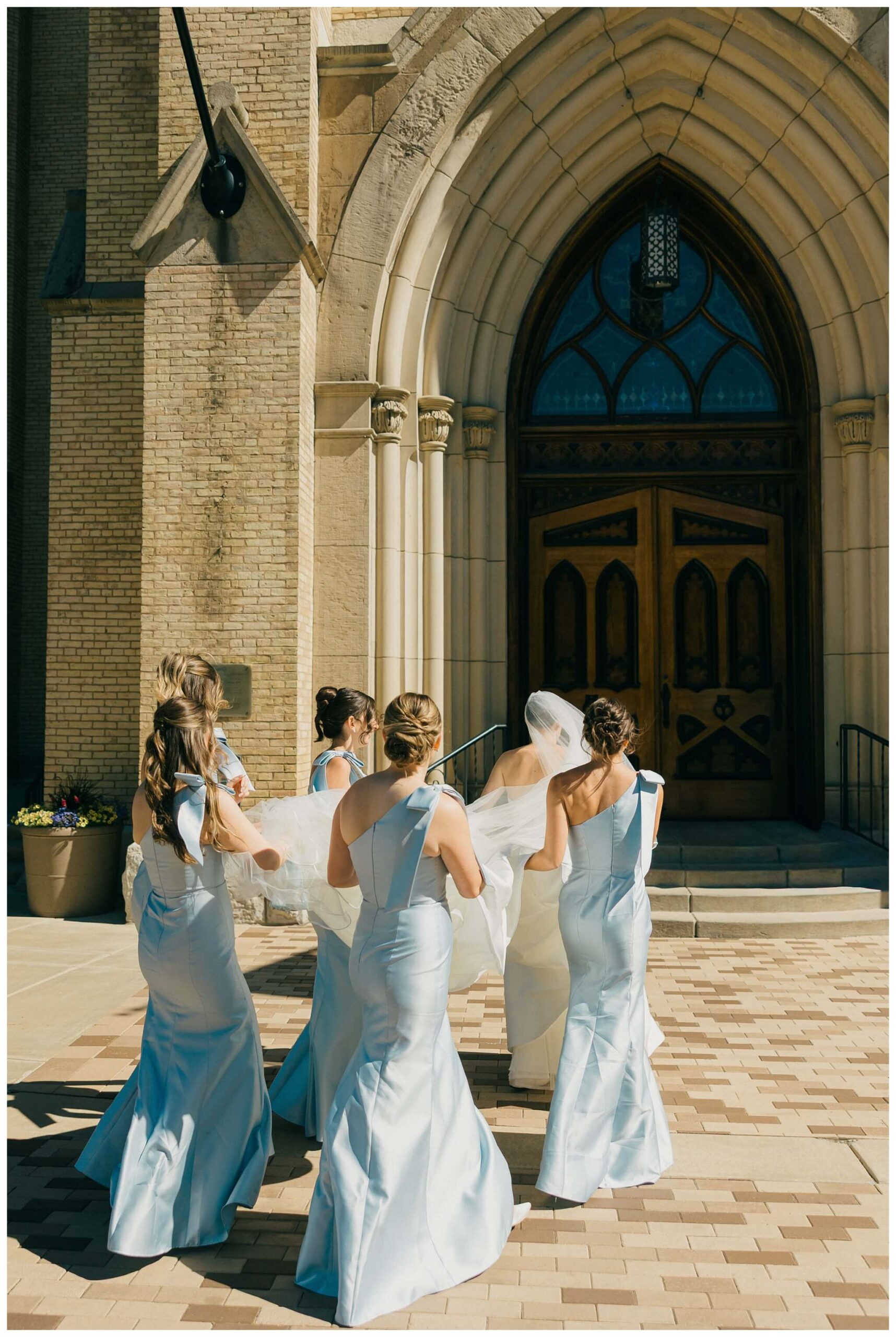 bride and bridesmaids walking to the basilica at Notre dame indiana by josh and andrea photography