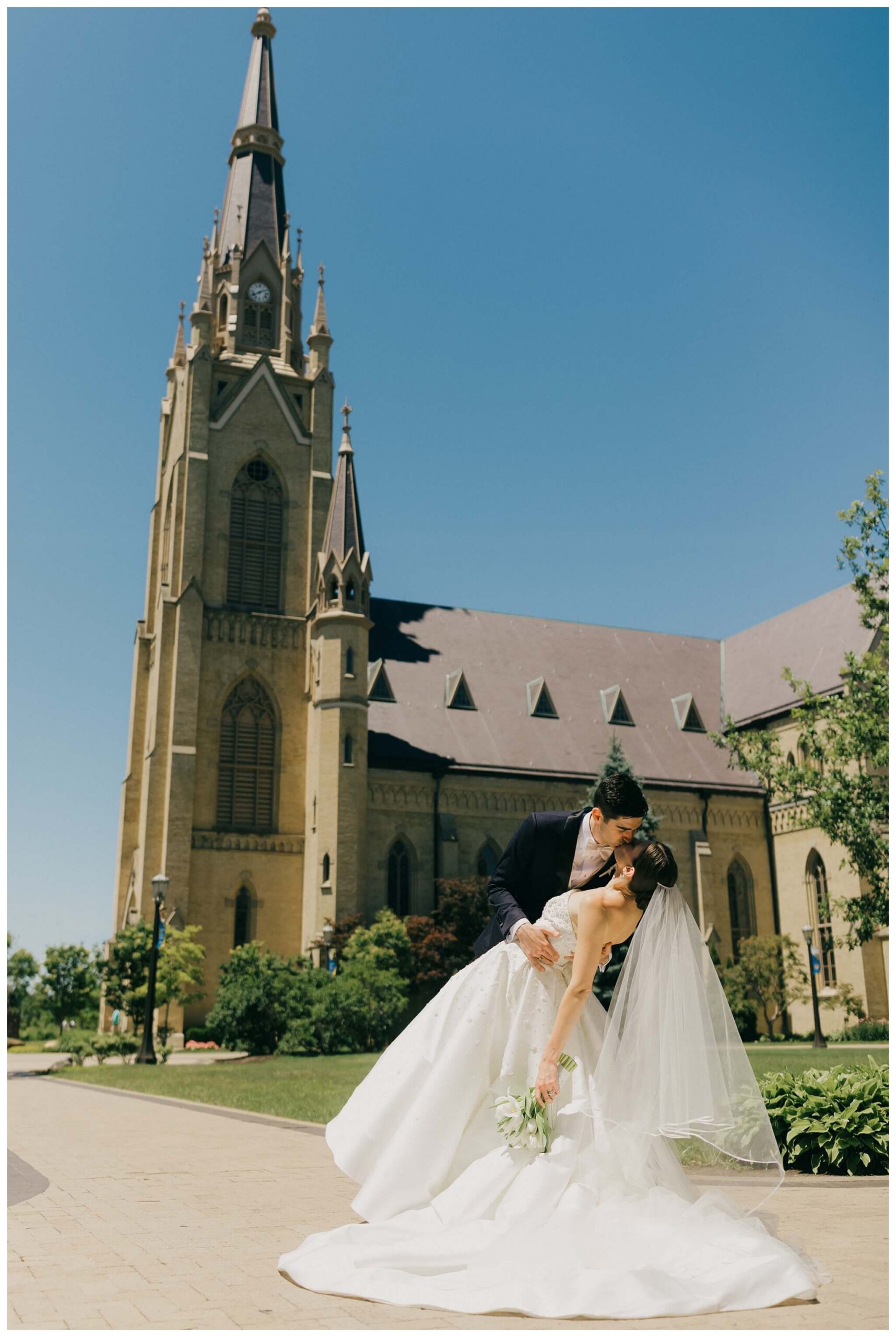 sunny bride and groom portrait in front of the basilica at Notre dame indiana by josh and andrea photography