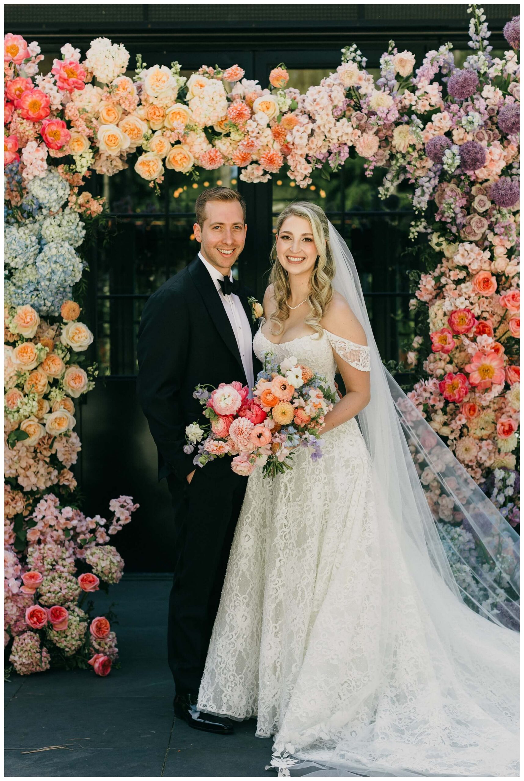 bride and groom standing under a floral arch at Shepherd's hollow golf club near clarkston michigan by josh and andrea photography 