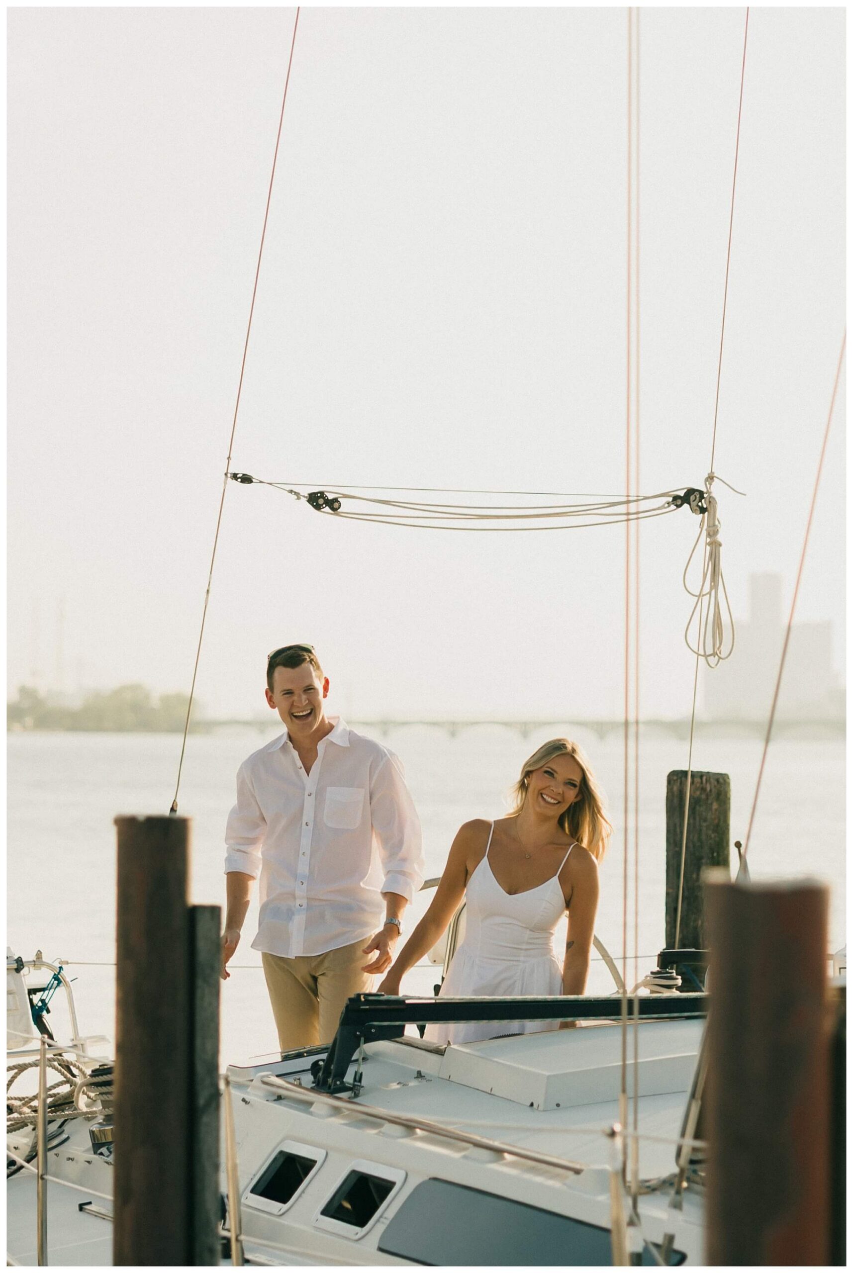 laughing couple on boat during sailboat engagement session in detroit by josh and andrea photography 