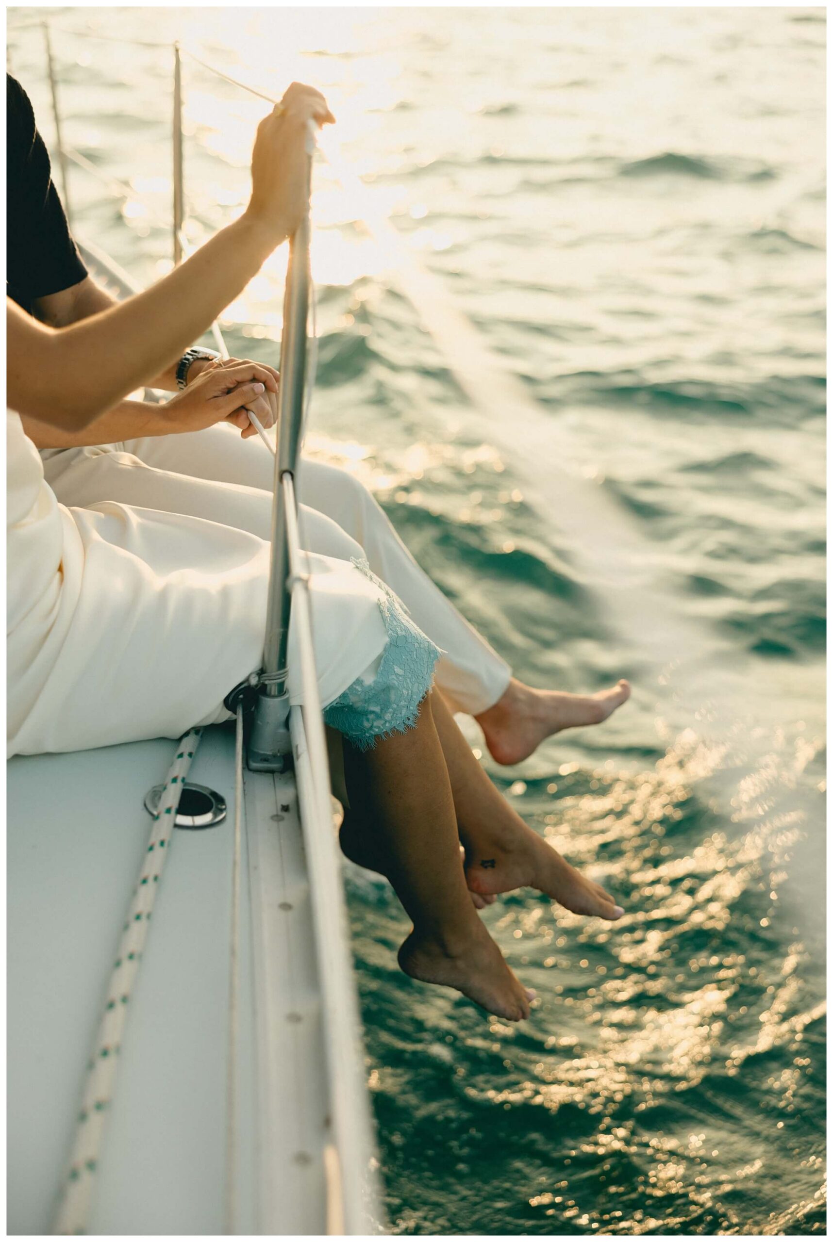 couple sitting on side of ship with water under sailboat engagement session in detroit by josh and andrea photography 