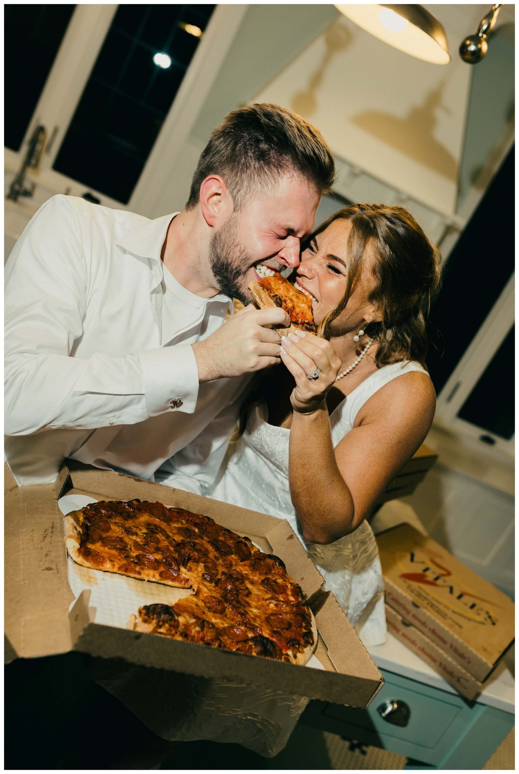 bride and groom share late night pizza snack at venue3two wedding by josh and andrea photography